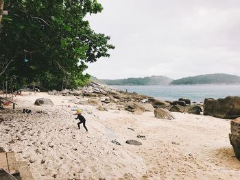 Rear view of man on beach against sky