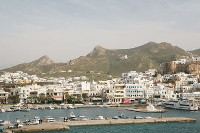 Boats moored at harbor by houses against sky