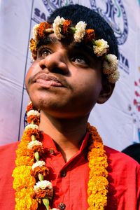 Close-up portrait of young man with red flower