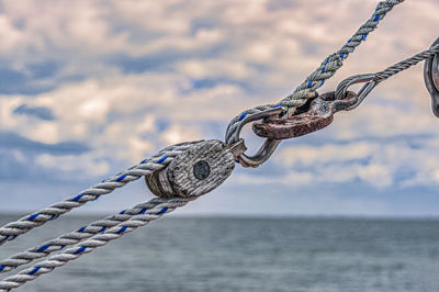 Close-up of chain hanging on rope against sea