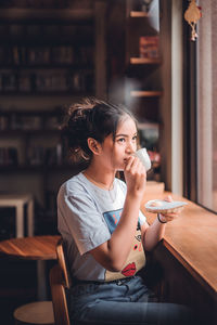 Young woman using smart phone while sitting on table