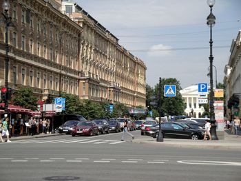 Cars on road amidst buildings in city during sunny day