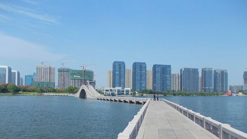 Sea by city skyline against sky