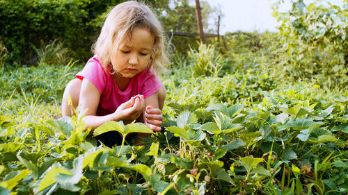 Girl looking away while standing by plants