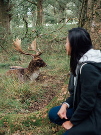 Woman standing by tree trunks in forest