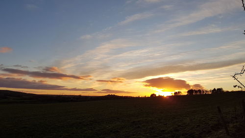 Scenic view of silhouette field against sky during sunset