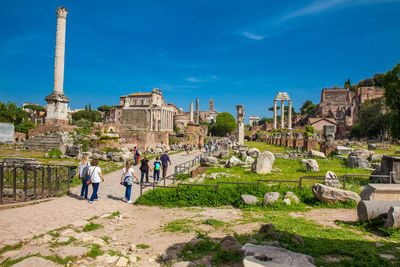 People at old ruins against sky