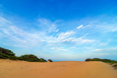Scenic view of sand dune against blue sky