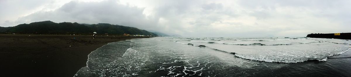 Scenic view of beach against cloudy sky