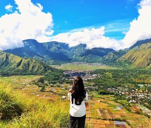 Rear view of woman standing on field against mountains