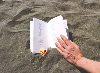 High angle view of hand on sand at beach