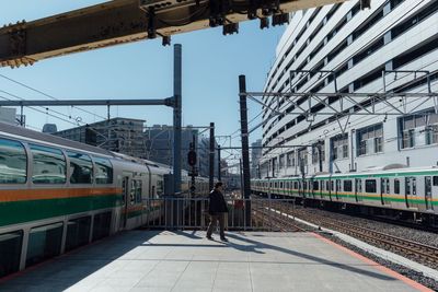 Train at railroad station in city against sky