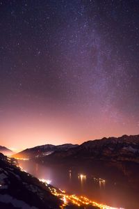 Scenic view of lake and mountains against sky at night