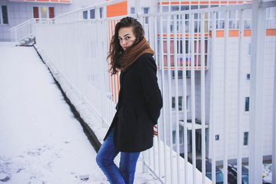 Portrait of young woman standing bu railing in snow