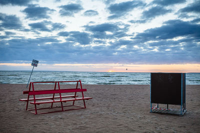 Lifeguard hut on beach against sky during sunset