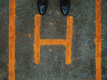 Black shoes by yellow letter h on road