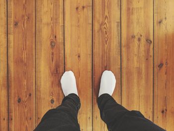 Low section of man standing on wooden floor