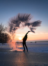 Silhouette man on beach against sky during sunset