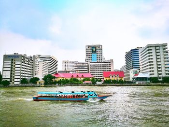 Boats in river by city against sky