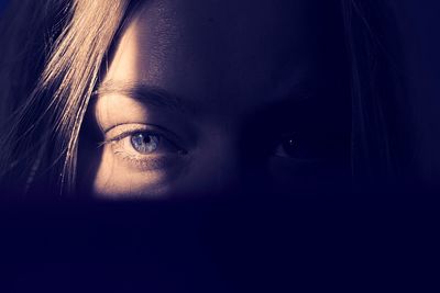 Portrait shot of beautiful girl with blue eyes standing in the shadows