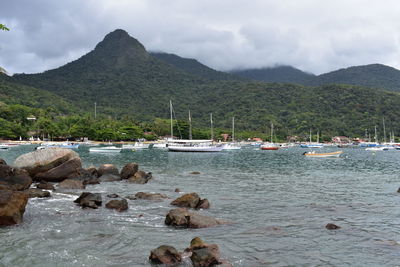 Sailboats in sea against mountains