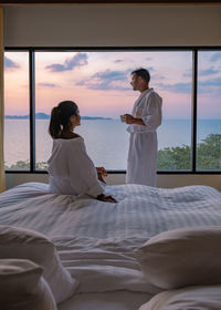 Rear view of woman sitting on bed at home