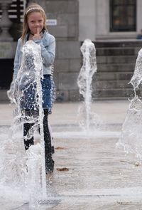 Portrait of smiling girl playing in fountain on street