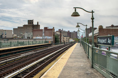 Railroad tracks in city against sky