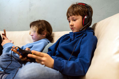 Kids playing with gadgets on the couch at home