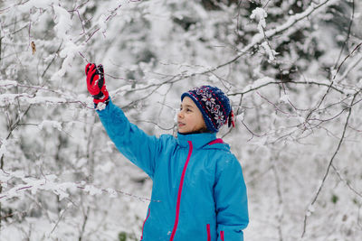 Girl standing in snow covered tree