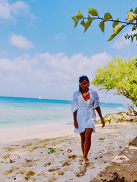 Rear view of woman standing at beach against sky