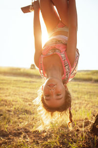 Portrait of girl hanging upside down on field