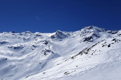 Low angle view of snowcapped mountains against clear blue sky