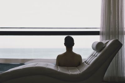 Rear view of man sitting by swimming pool