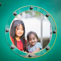 Smiling girl reflecting on circle shaped mirror