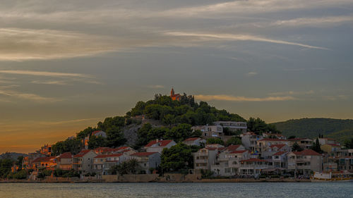 Townscape by sea against sky during sunset