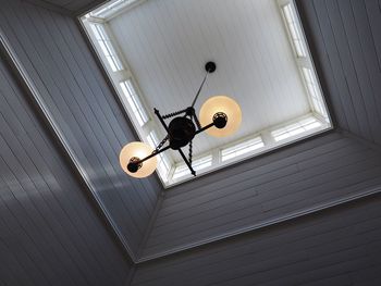 Low angle view of illuminated lamp hanging on ceiling in building