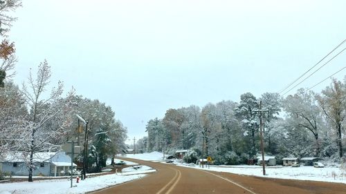 Road amidst trees against clear sky during winter