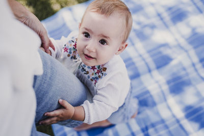  cute baby girl holding leg of mother at park