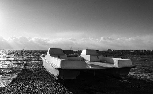 Boat moored on shore against sky