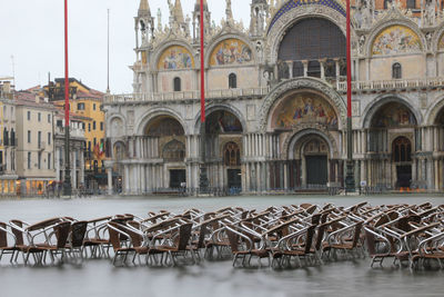 Saint mark basilica during tide in venice in italy and many chairs of bar underwater in winter