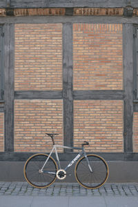 Bicycle parked on brick wall of building