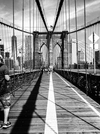 People on bridge against sky in city