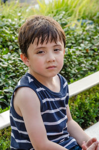 Portrait of boy sitting against plants