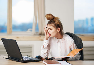 Young woman using mobile phone while sitting on table