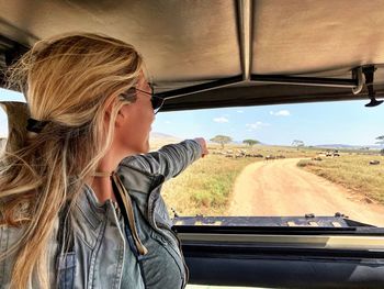 Woman pointing at animals while sitting in vehicle during safari
