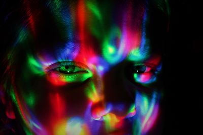 Close-up portrait of girl with illuminated lights on face in darkroom