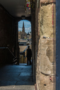 Rear view of people walking on alley amidst buildings in city