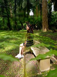 Rear view of woman sitting on field