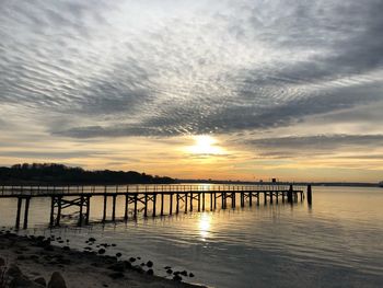 Pier over sea against sky during sunset